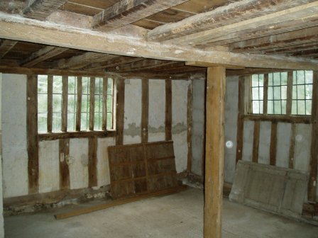 The kitchen before work began showing two of the old shutters and the rotten central beam