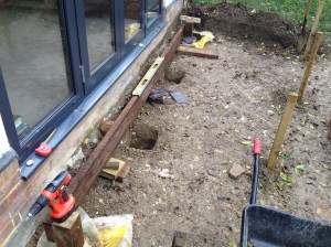 Holes for the posts, lined up with the first joist The stakes mark later holes.